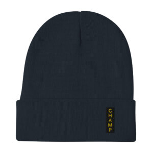 The Subtle & Mighty CHAMP Embroidered Beanie features a dark color, folded brim, and CHAMP in yellow on a vertical patch.