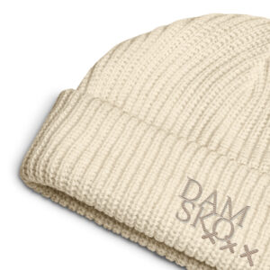 A close-up of the 3-crosses AMSTERDAMSKO embroidered FISHERMAN Beanie in cream, featuring DAM SKQ and three light gray Xs stitched on the folded brim, highlights the distinctive and stylish AMSTERDAMSKO design of this knitted accessory.