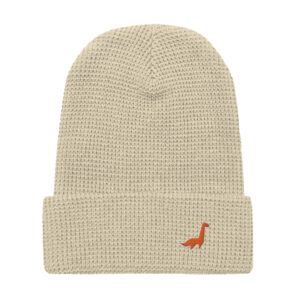 LaDino Waffle Beanie in beige with a folded brim, featuring a small orange dinosaur logo embroidered on the front. This cozy knit beanie blends comfort and playful style, perfect for any casual outing.