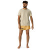 A curly-haired man in a beige T-shirt and CHAMP Golden Athletic Shorts stands barefoot against a white background, embodying the spirit of a CHAMP. A curly-haired man in a beige T-shirt and CHAMP Golden Athletic Shorts stands barefoot against a white background, embodying the spirit of a CHAMP.