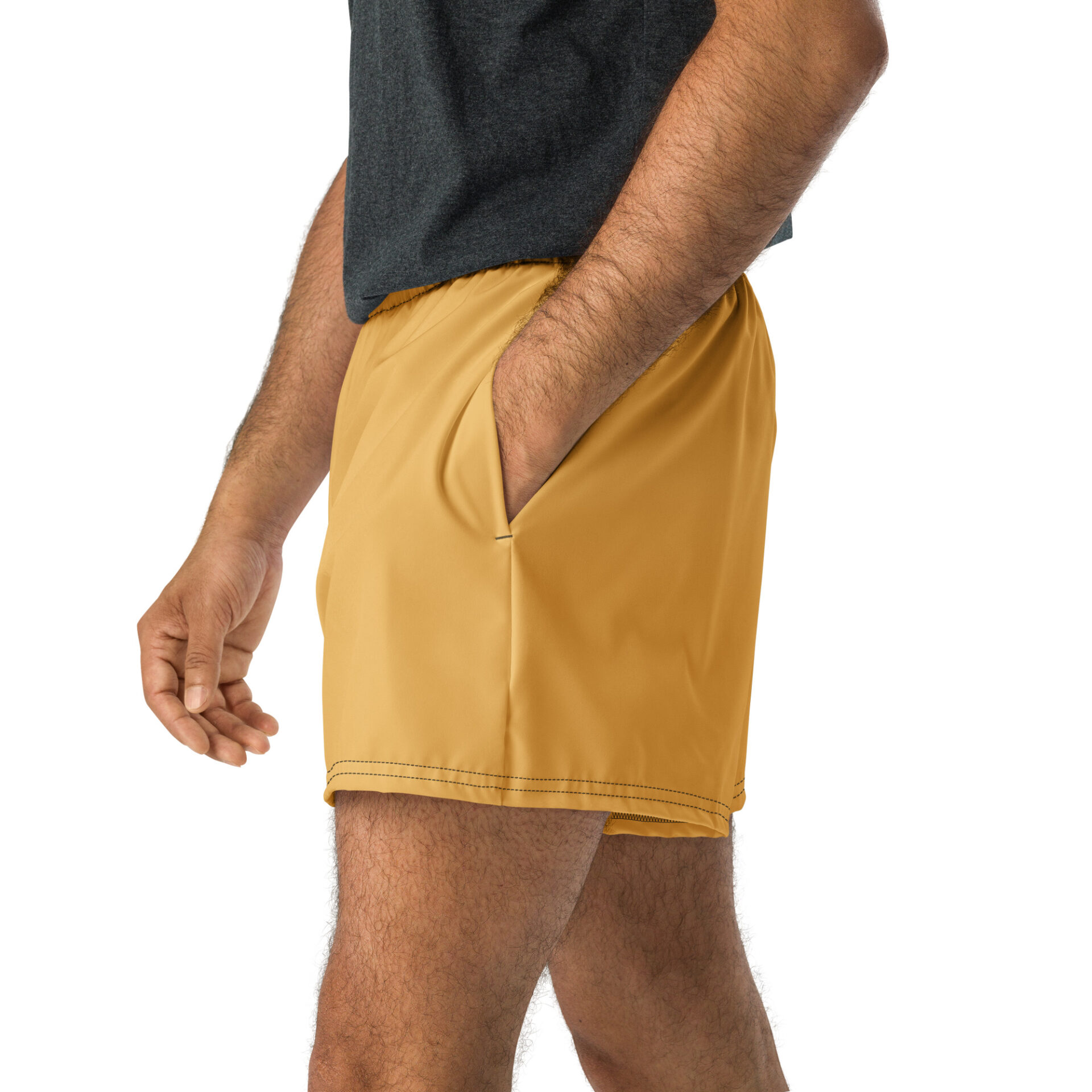 Someone wearing a dark gray shirt and CHAMP Golden Athletic Shorts stands with one hand in the shorts pocket against a white background. Someone wearing a dark gray shirt and CHAMP Golden Athletic Shorts stands with one hand in the shorts pocket against a white background.