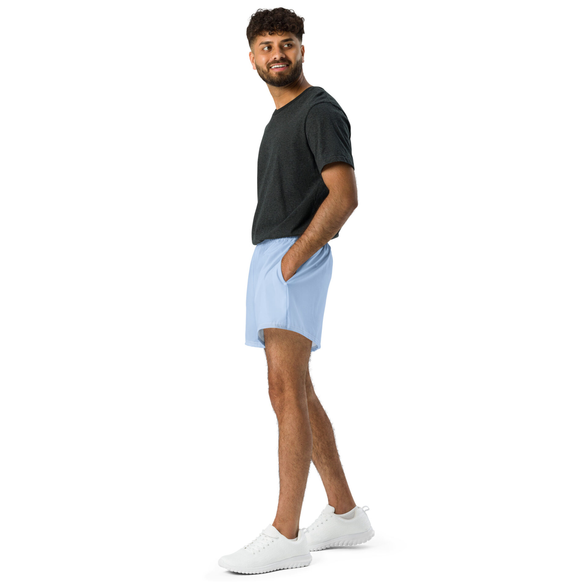 A man stands against a white background, smiling to the side. He wears MJL Athletic Shorts in light blue, paired with a dark gray t-shirt and white sneakers, his hands casually resting in the shorts pockets. A man stands against a white background, smiling to the side. He wears MJL Athletic Shorts in light blue, paired with a dark gray t-shirt and white sneakers, his hands casually resting in the shorts pockets.