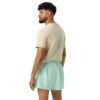 A man with dark hair and a beard wears a beige t-shirt and light green MJL Athletic Shorts, standing turned slightly away against a plain white background. A man with dark hair and a beard wears a beige t-shirt and light green MJL Athletic Shorts, standing turned slightly away against a plain white background.