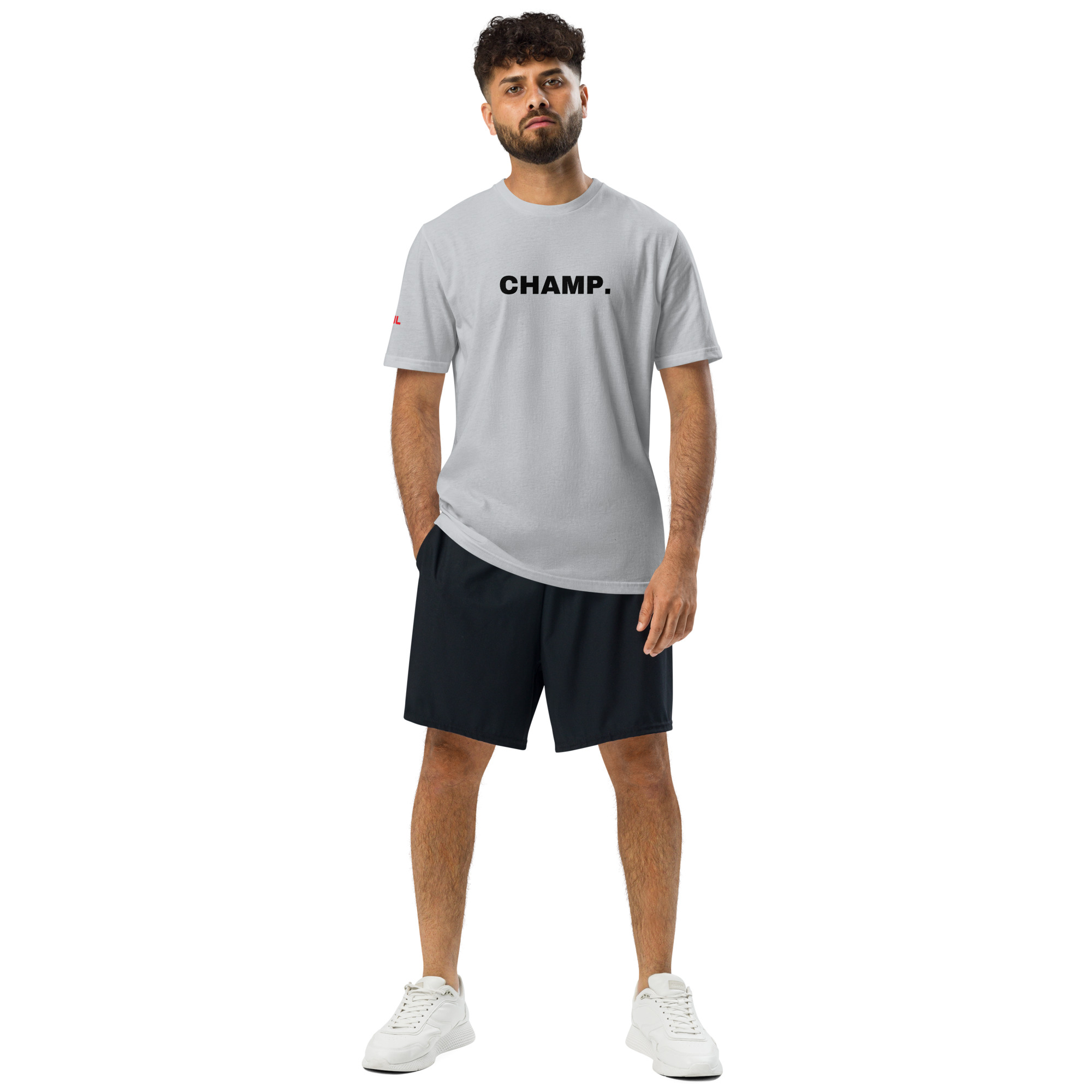 A man with curly hair and a beard wears the Under ArmourⓇ athletic t-shirt embroidered CHAMP, paired with black shorts and white sneakers, standing against a white background. A man with curly hair and a beard wears the Under ArmourⓇ athletic t-shirt embroidered CHAMP, paired with black shorts and white sneakers, standing against a white background.